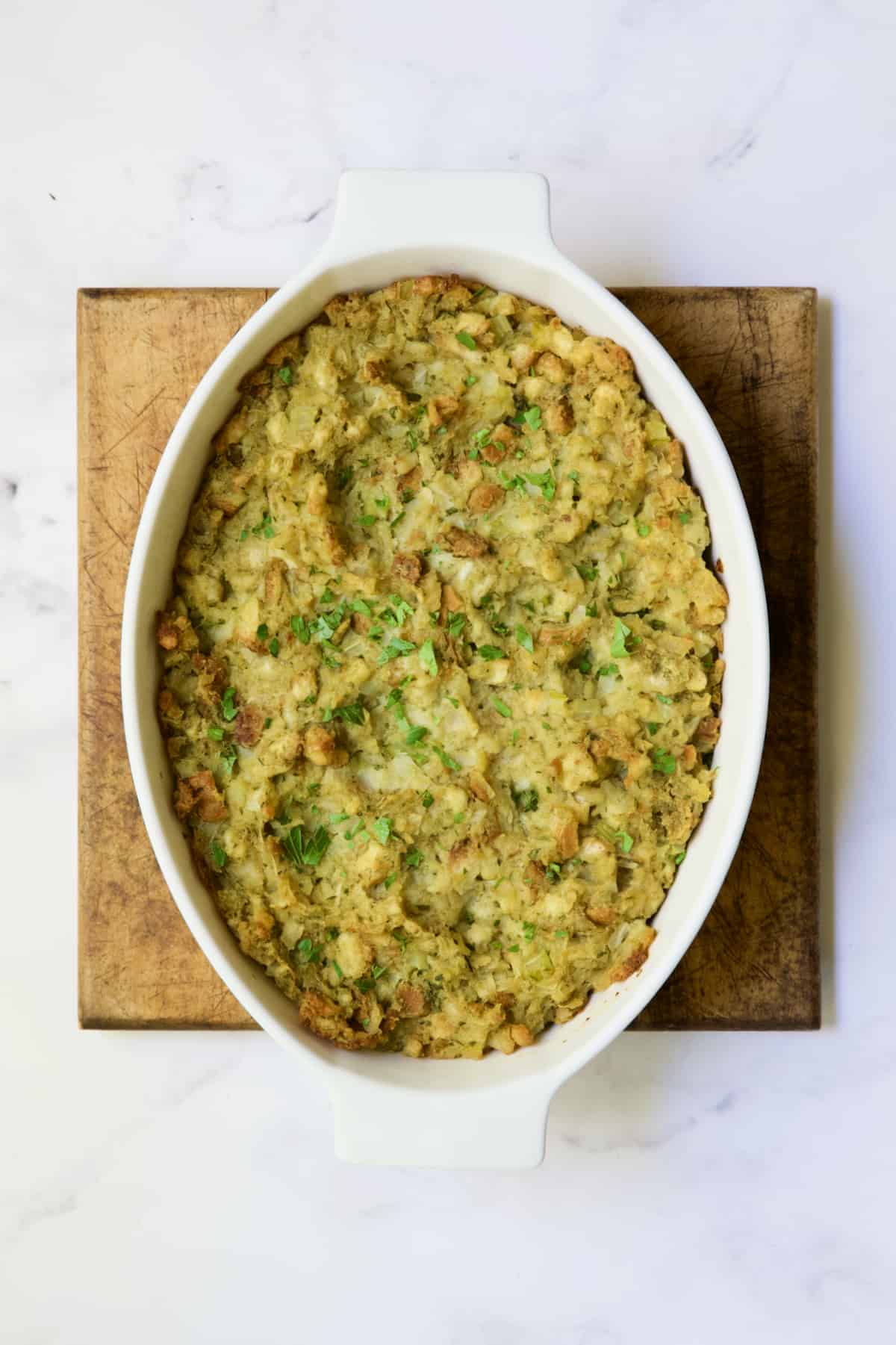 Traditional stuffing in oval baking dish on wood trivet.