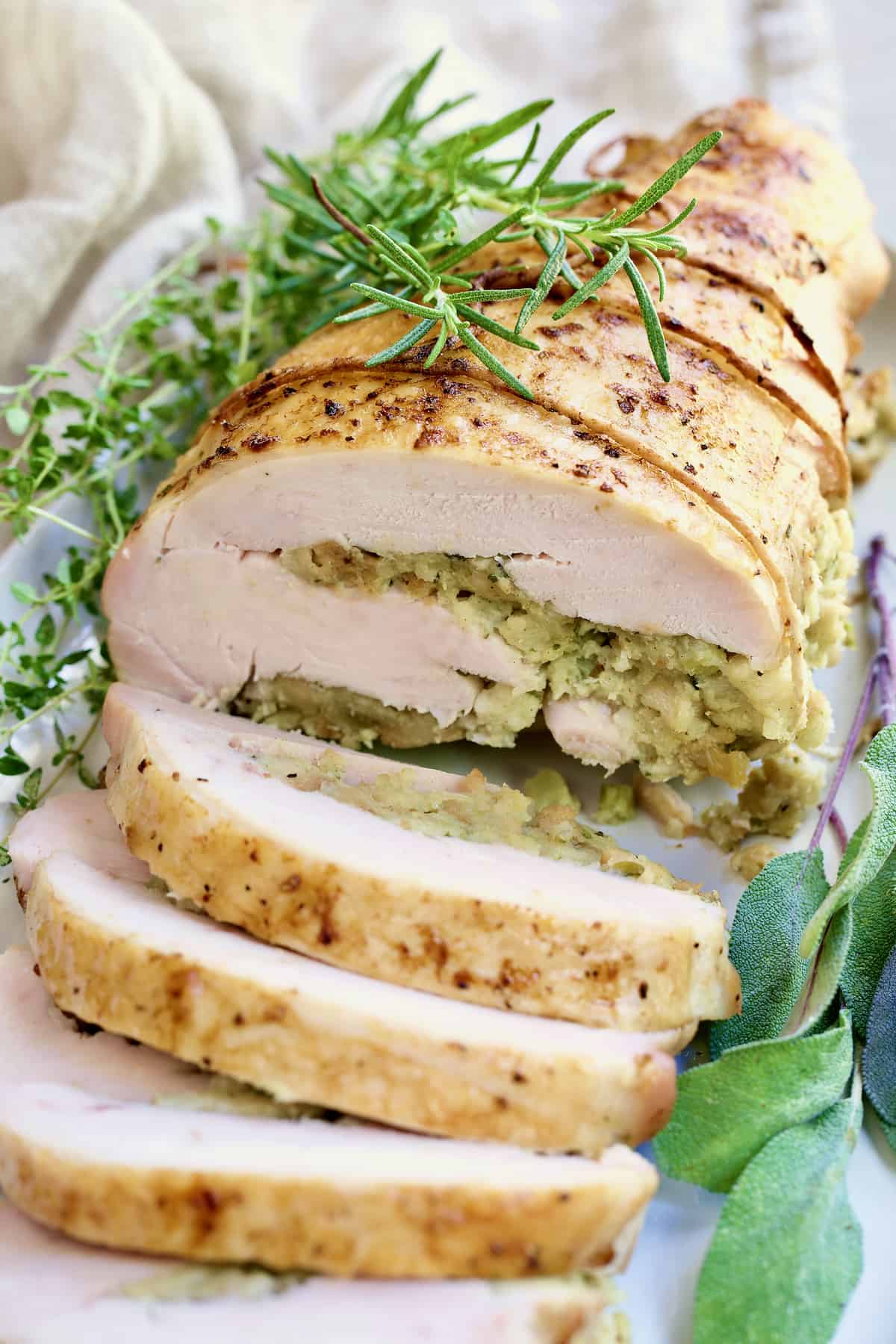 Close-up photo of Roast Turkey Breast with Traditional Stuffing garnished with fresh herbs.