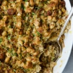Sausage Stuffing with Fennel and Leeks in white oval gratin dish with serving spoon.