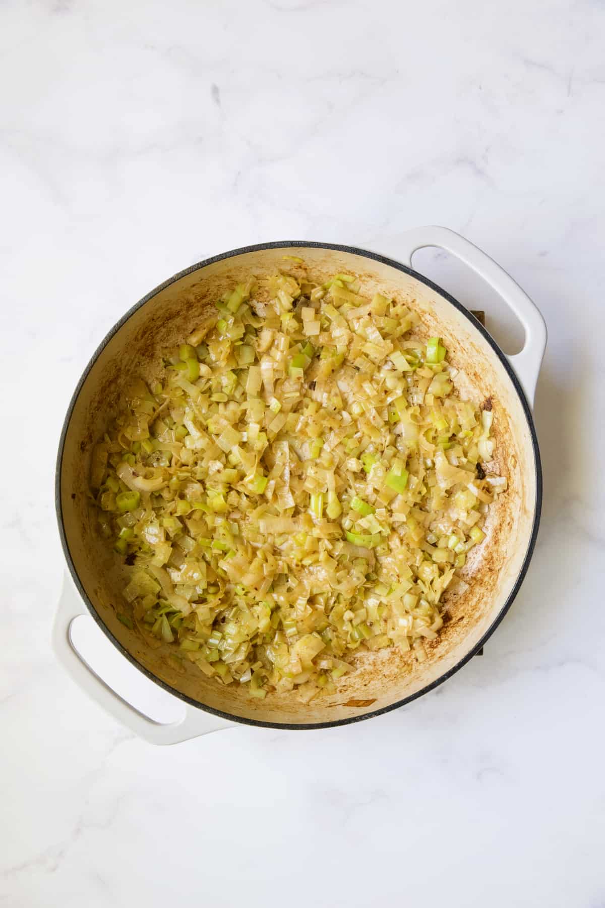 Cooked leeks in white enamel cast iron skillet.