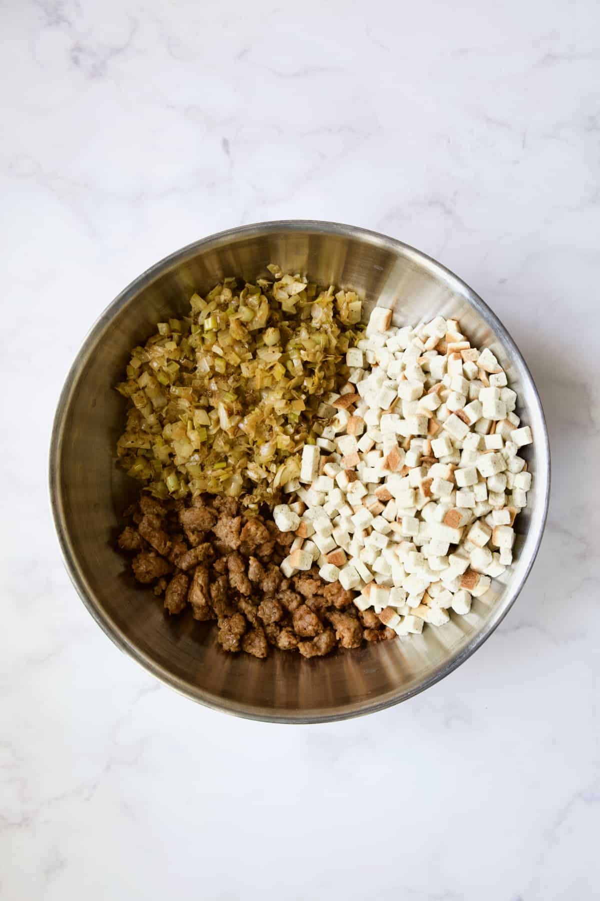 Cooked ingredients for Sausage Stuffing with Fennel and Leeks in stainless steel bowl before being mixed together.