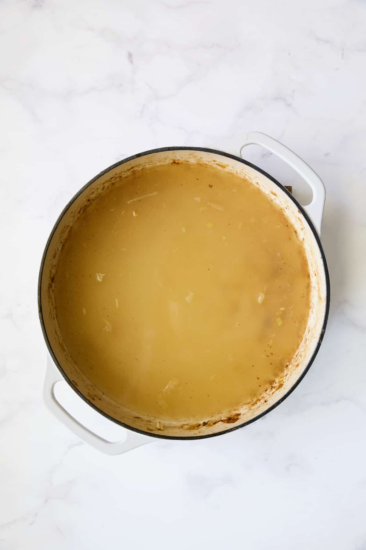 Chicken broth in white enamel cast iron skillet.