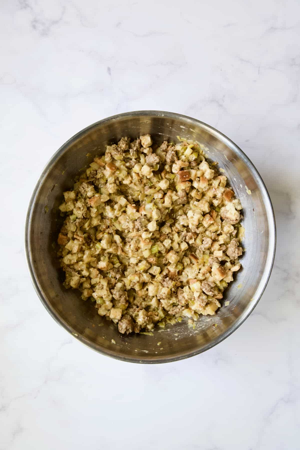 Ingredients for Sausage Stuffing with Fennel and Leeks mixed together in stainless steel bowl.