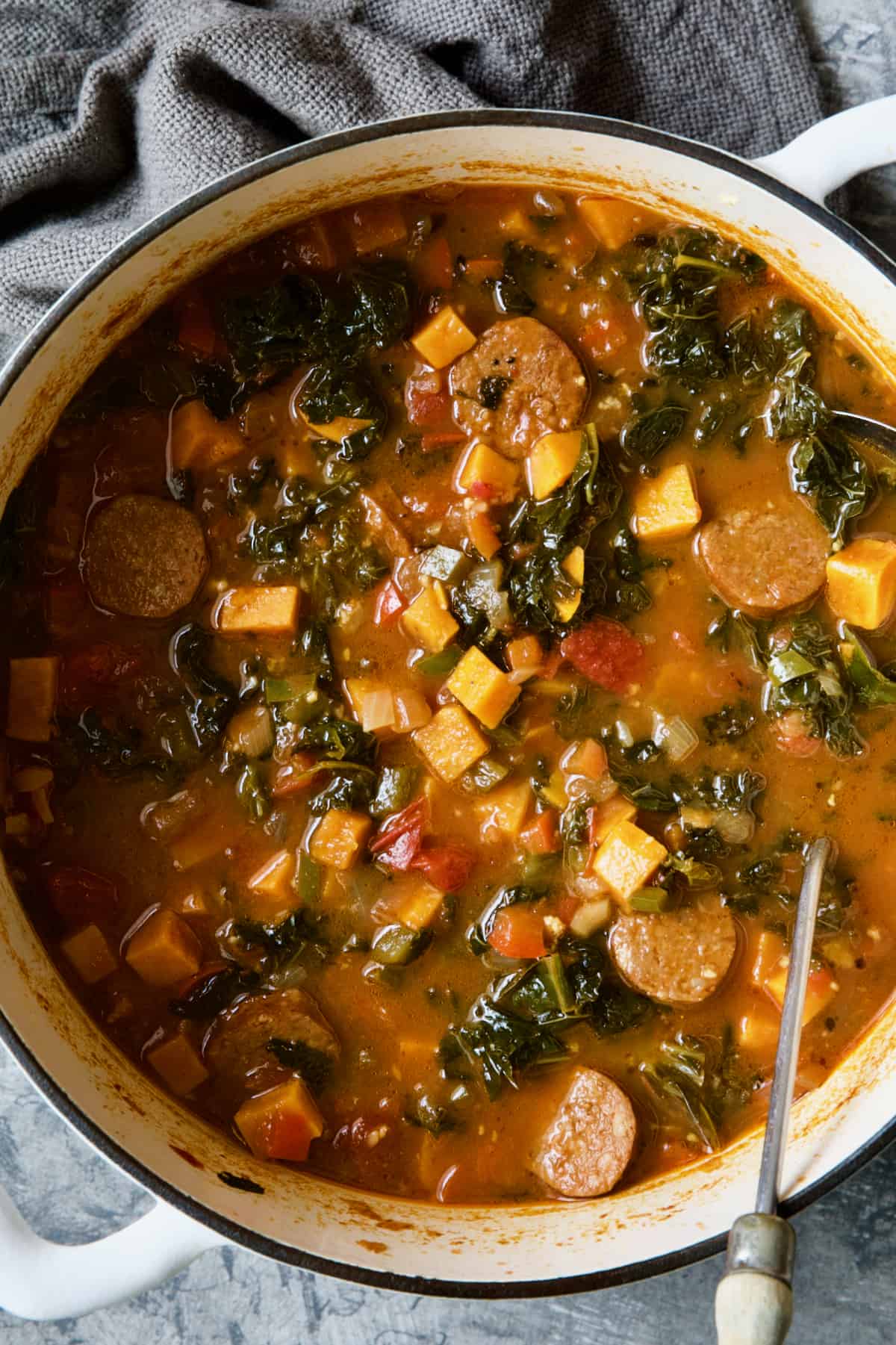 Chorizo Sweet Potato Stew with Kale in Dutch oven with soup ladle.