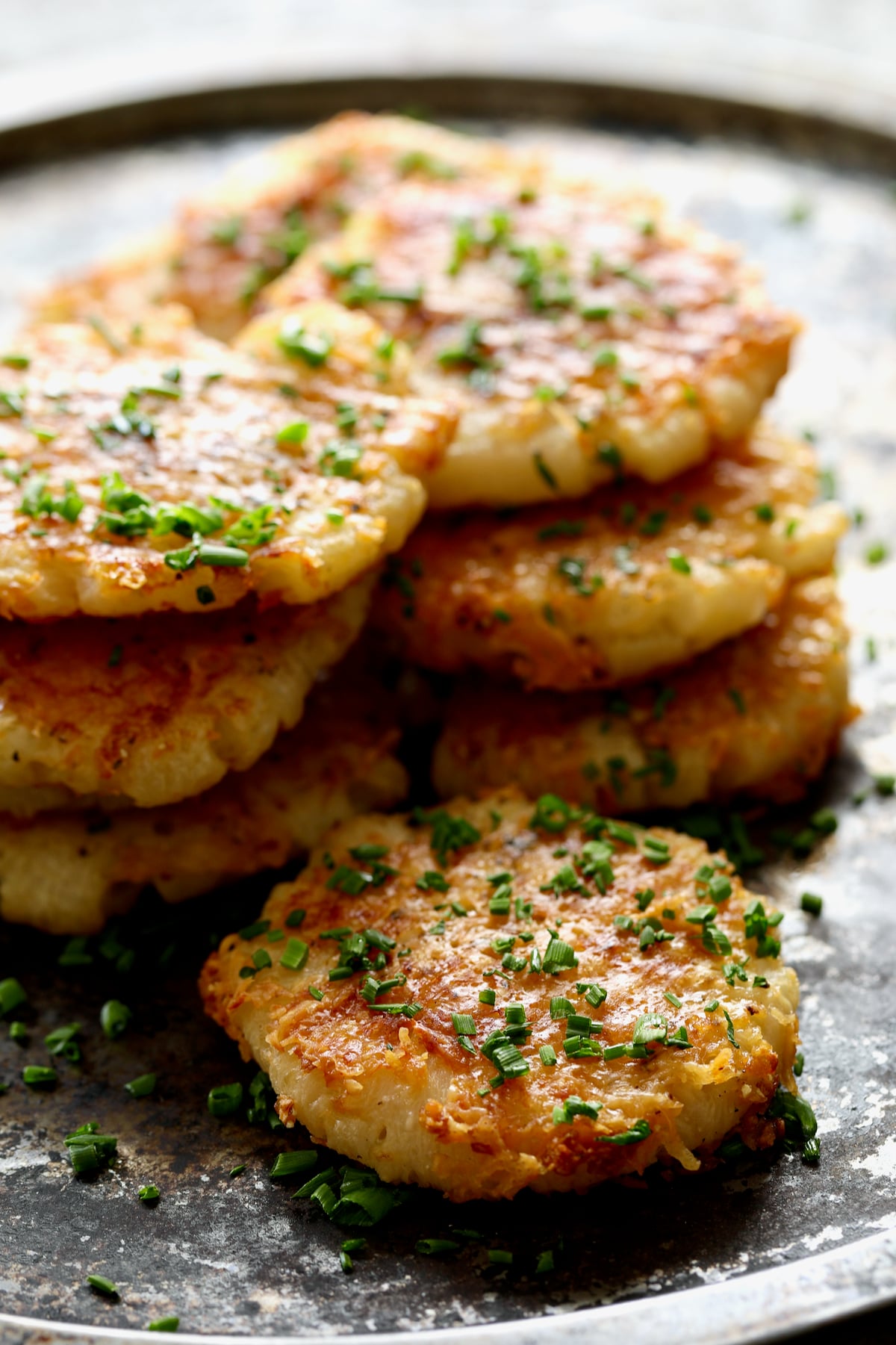Stacked Parmesan Crusted Crushed Turnips on stainless steel tray.