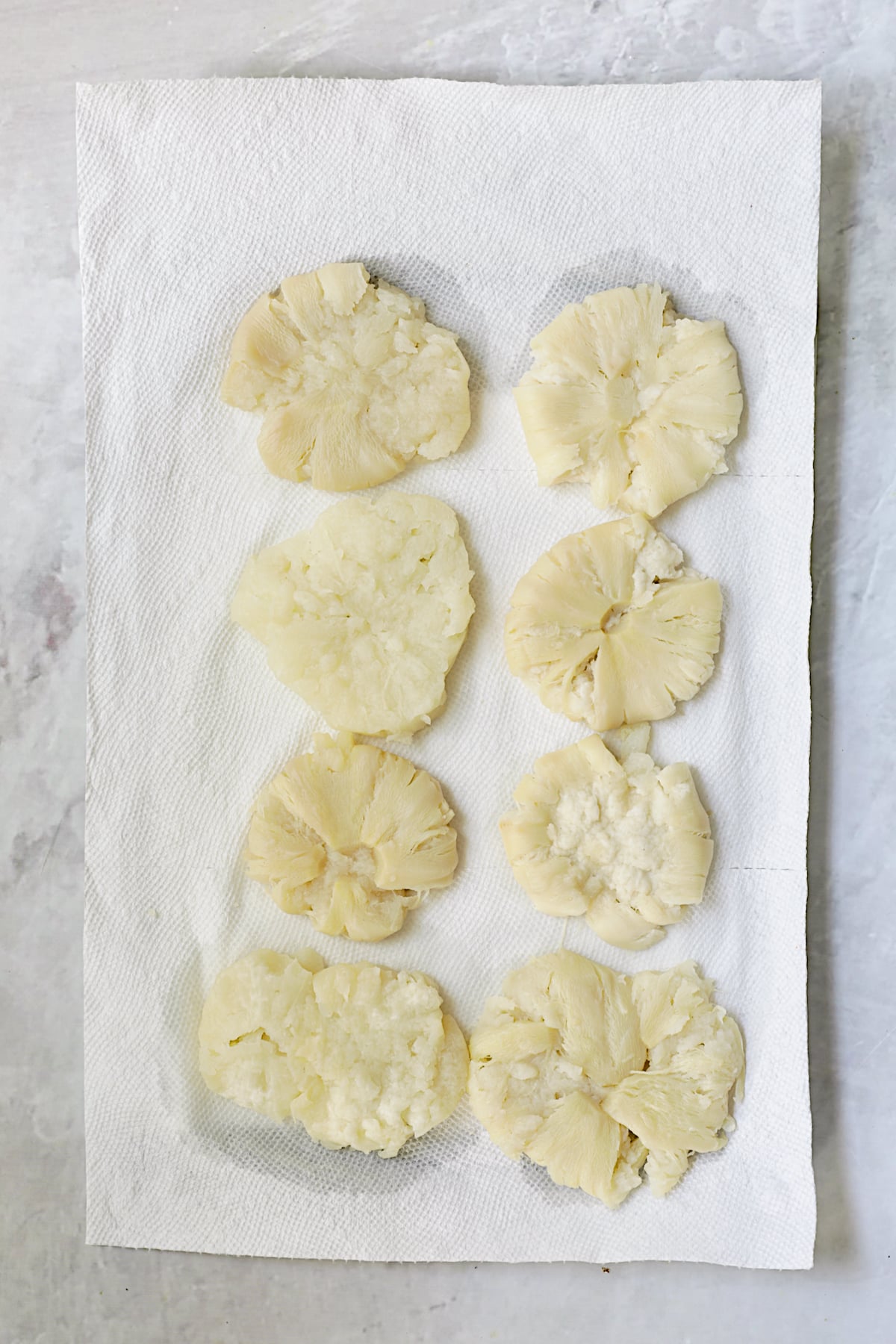 Eight smashed turnips on paper towels.