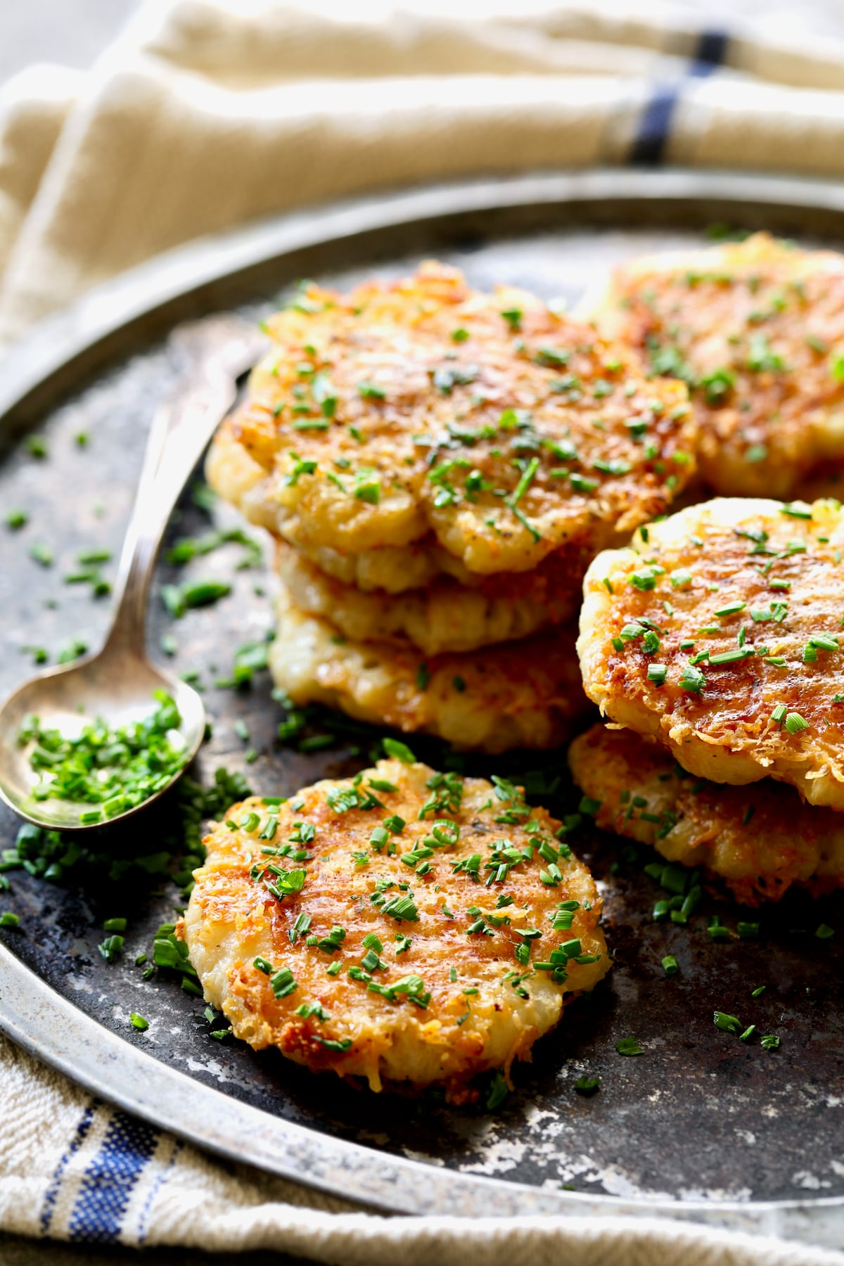Parmesan Crusted Crushed Turnips on stainless steel tray garnished with chives.