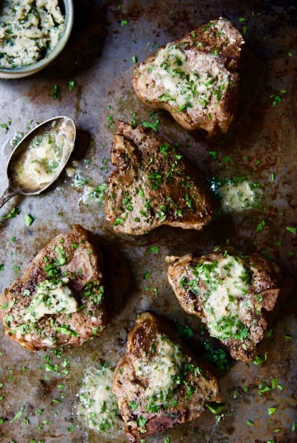 Seared Lamb Chops with Anchovy Butter on patinated baking sheet.