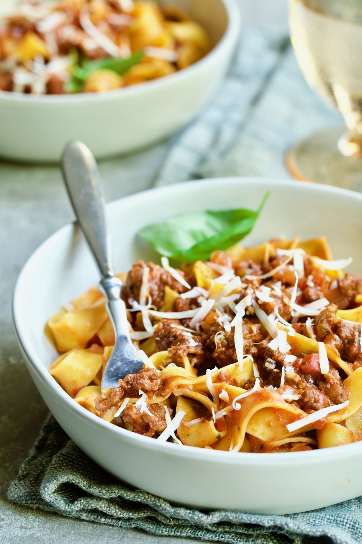 Slow Cooker Spicy Sausage and Pepper Ragu over pappardelle in white bowl with fork.