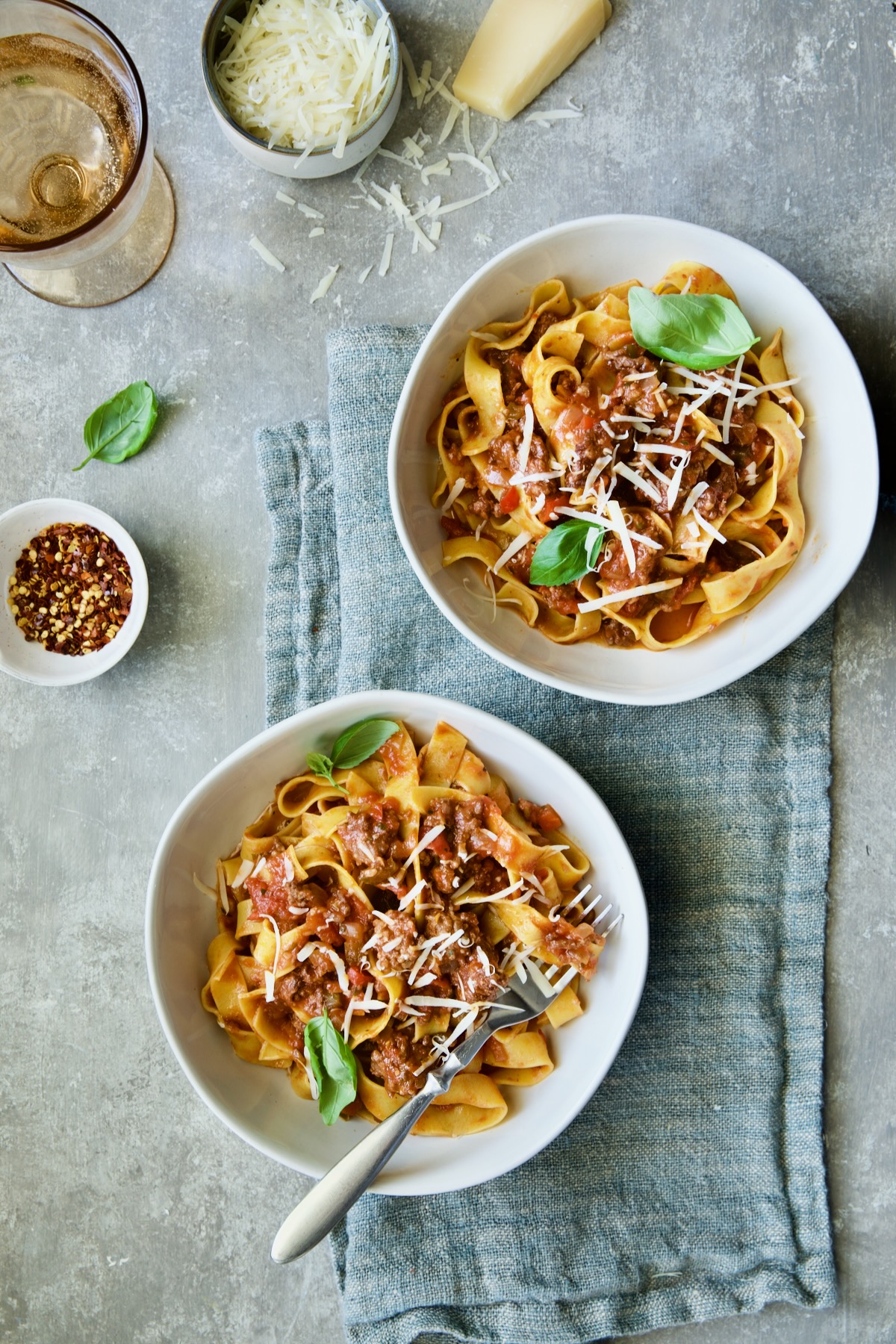 Two bowls of Slow Cooker Spicy Sausage and Pepper Ragu on blue napkin.