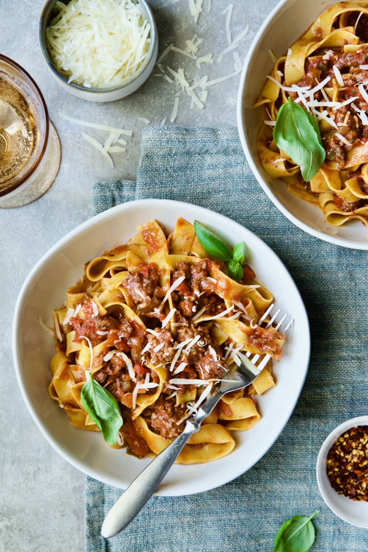 Slow Cooker Spicy Italian Sausage Ragu in bowls sprinkled with cheese and garnished with fresh basil.