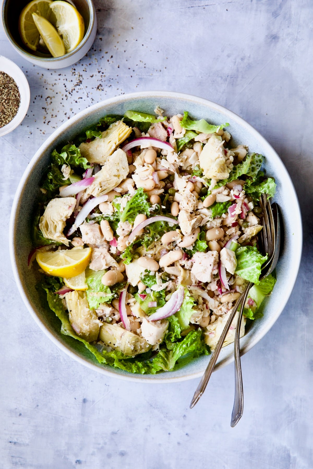 Tuna, White Bean and Artichoke Salad in serving bowl with serving utensils.
