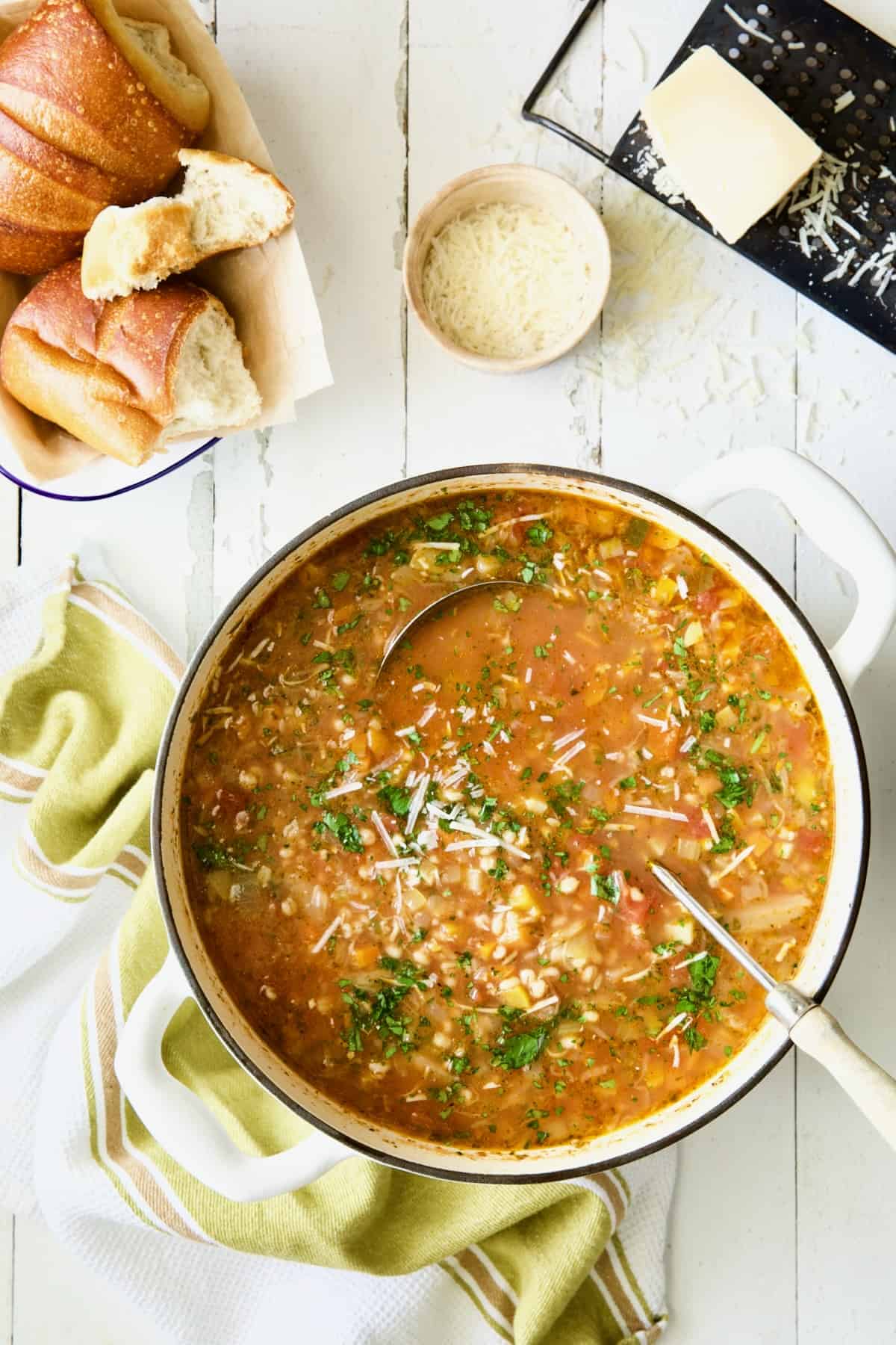 Pot of Vegetable Barley Soup on white distressed background.