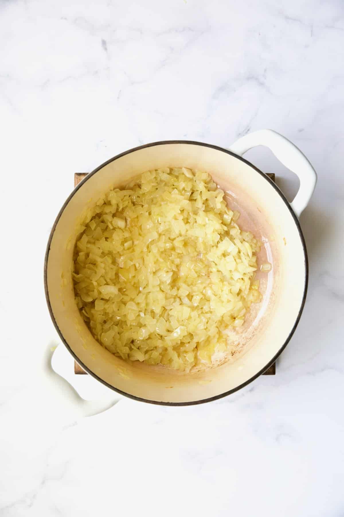 Cooked onions in white Dutch oven.
