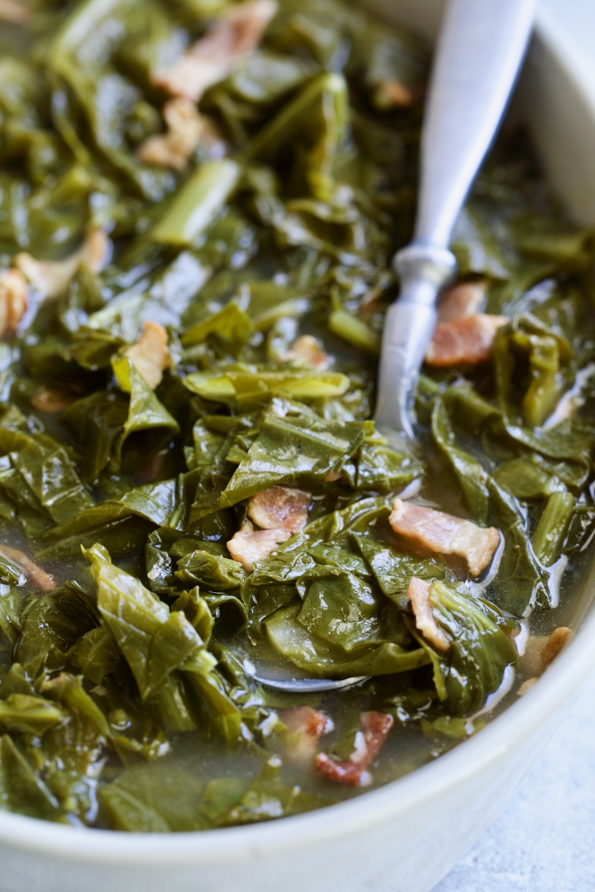 Braised Southern Greens in bowl with spoon scooping some up.