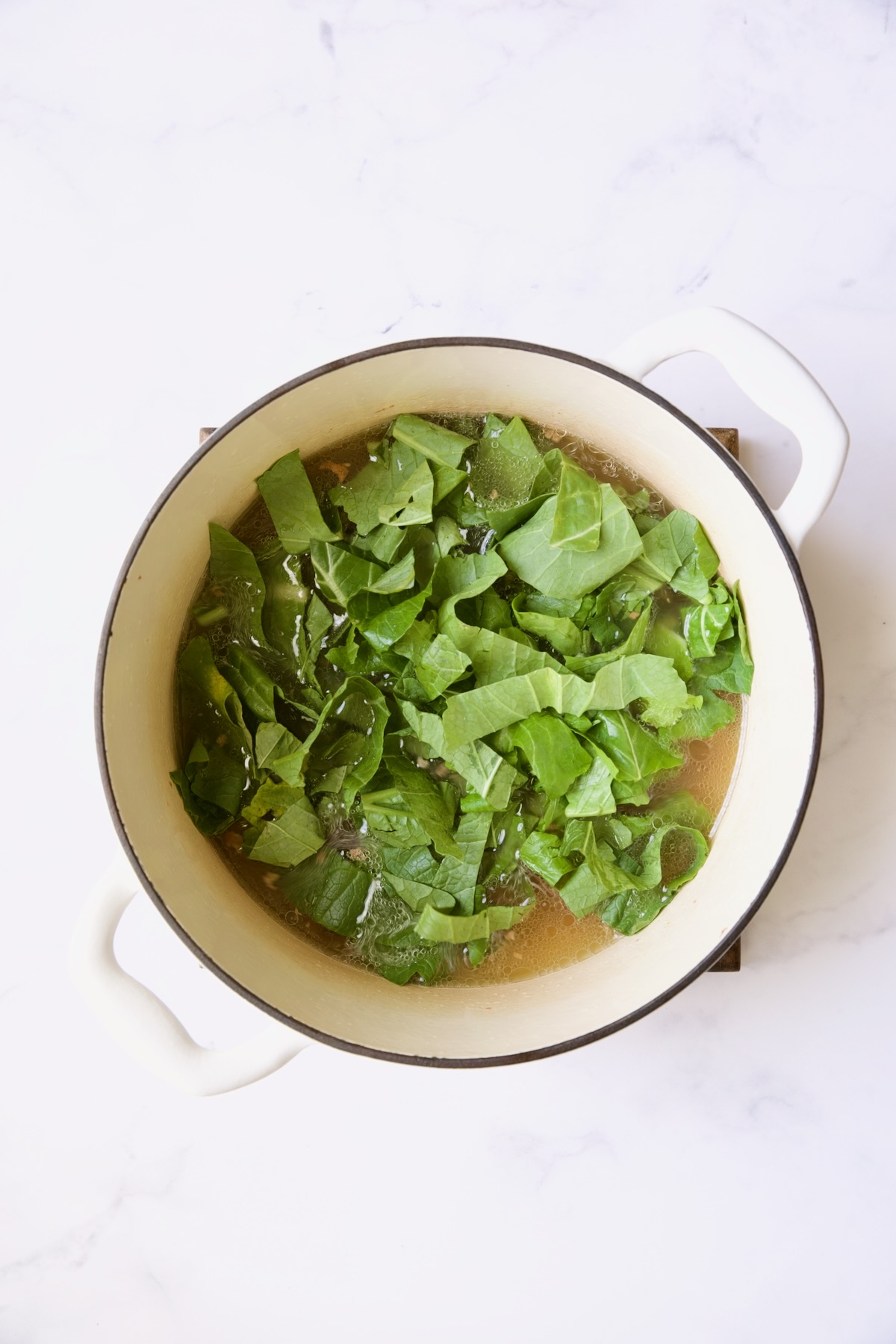 Greens in white Dutch oven before being cooked.
