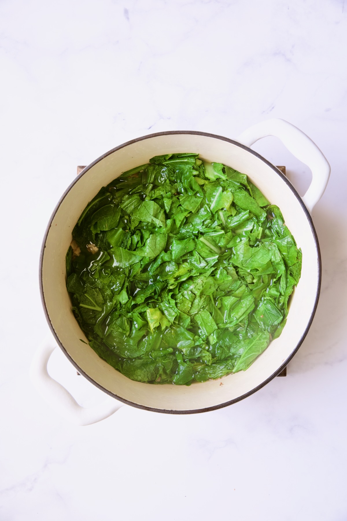 Greens in white Dutch oven before being cooked.