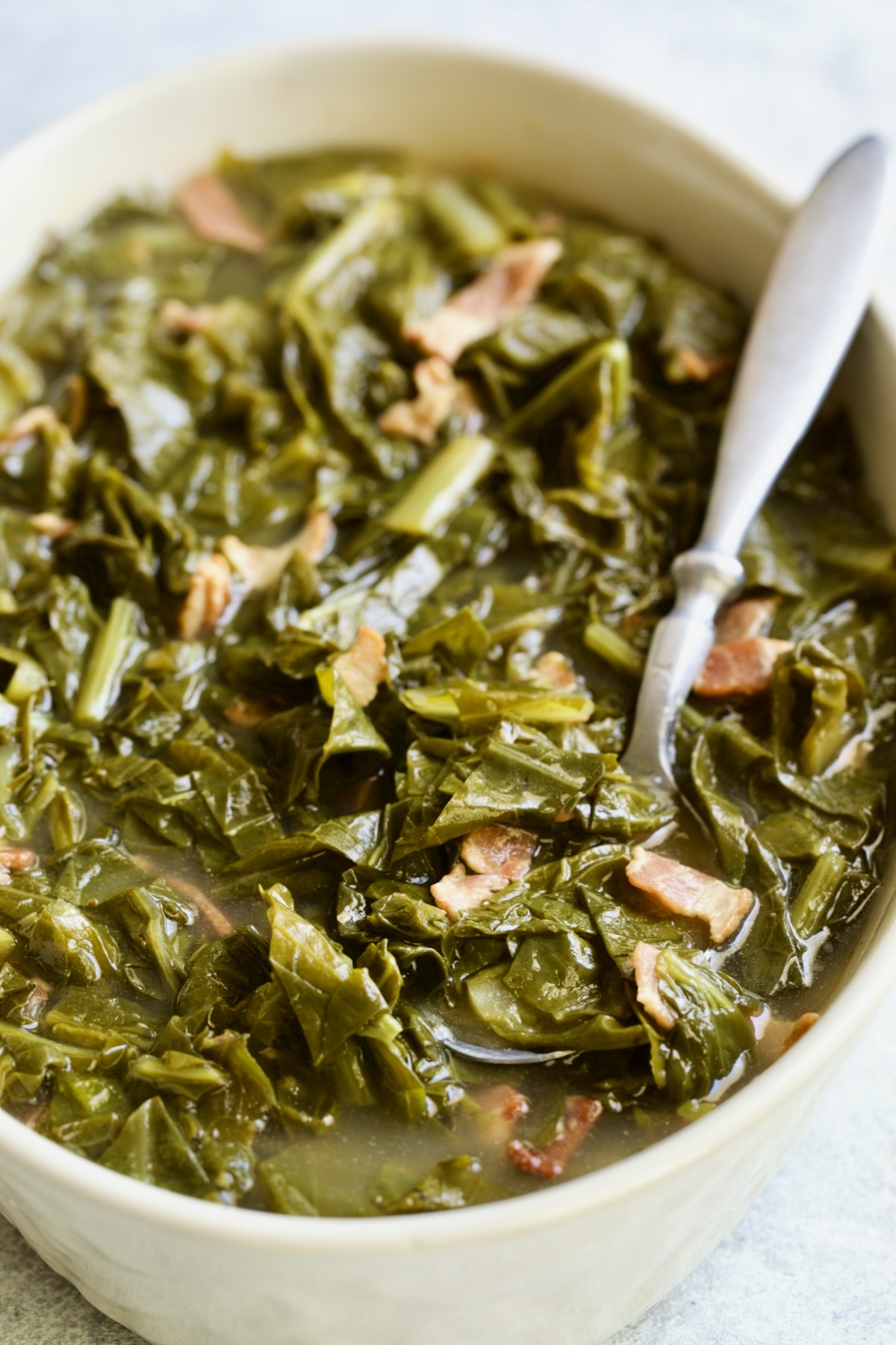 Braised Southern Greens in oval serving bowl with serving spoon.