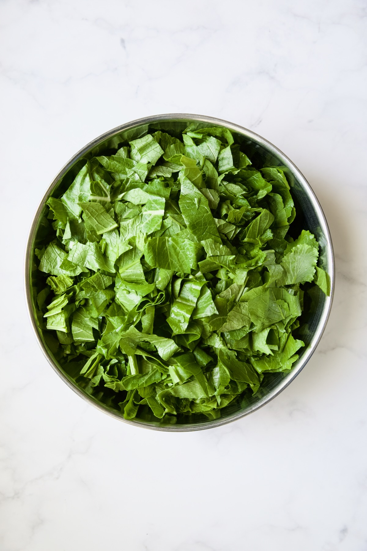 Uncooked greens in stainless steel bowl.
