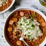 Easy Red Beans and Rice in white bowl on light blue background with fork scooping beans out.