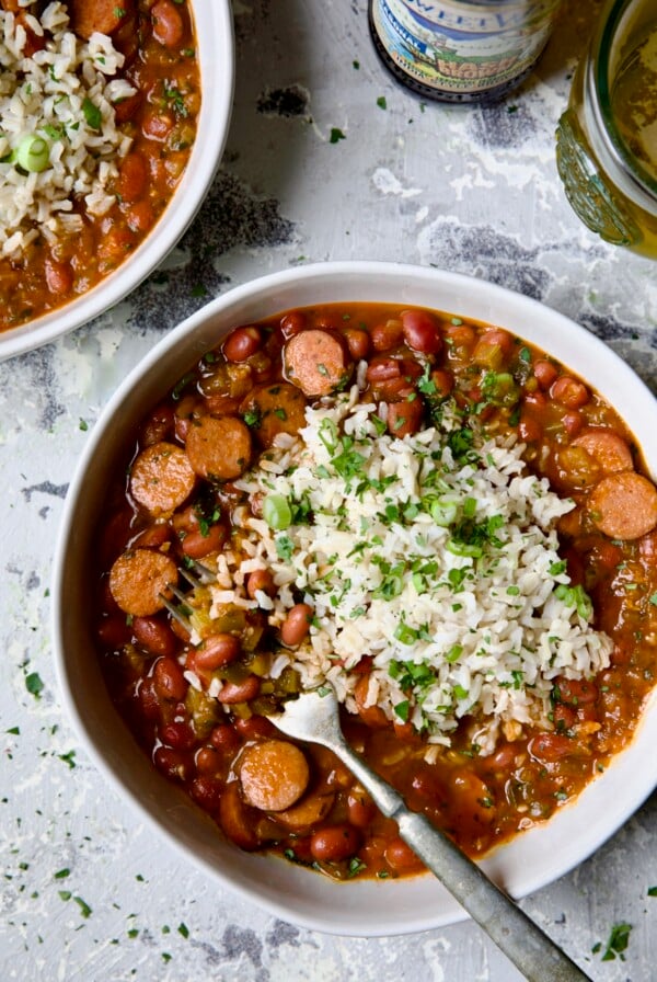Easy Red Beans and Rice in white bowl on light blue background with fork scooping beans out.