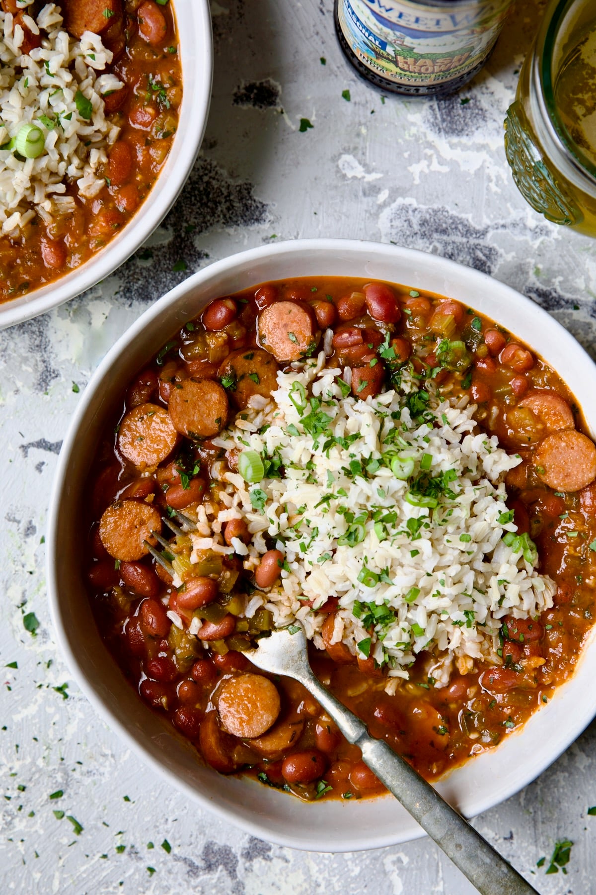 Easy Red Beans and Rice in white bowl on light blue background with fork scooping beans out.