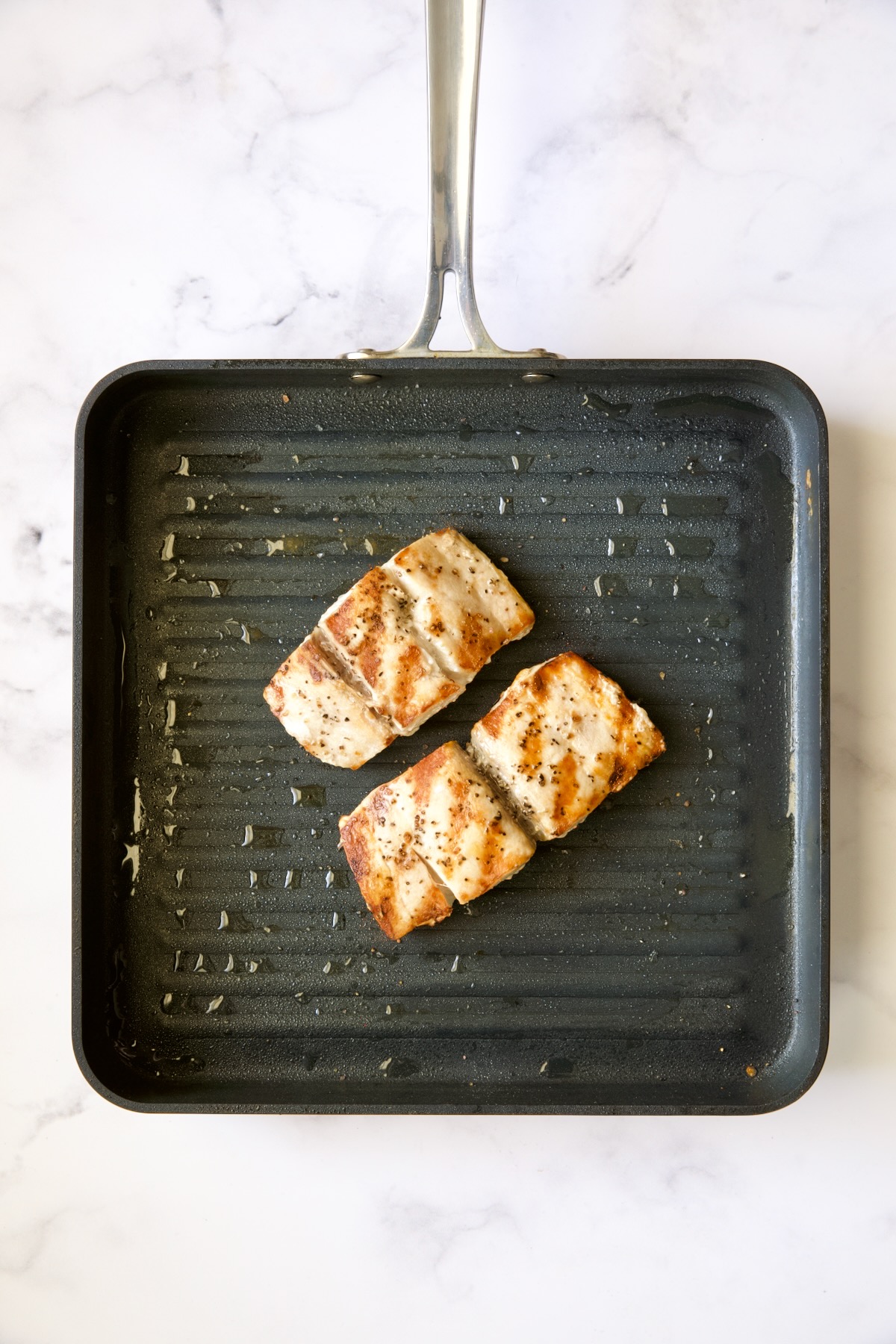 Two pieces of mahi-mahi on nonstick grill pan after being grilled.