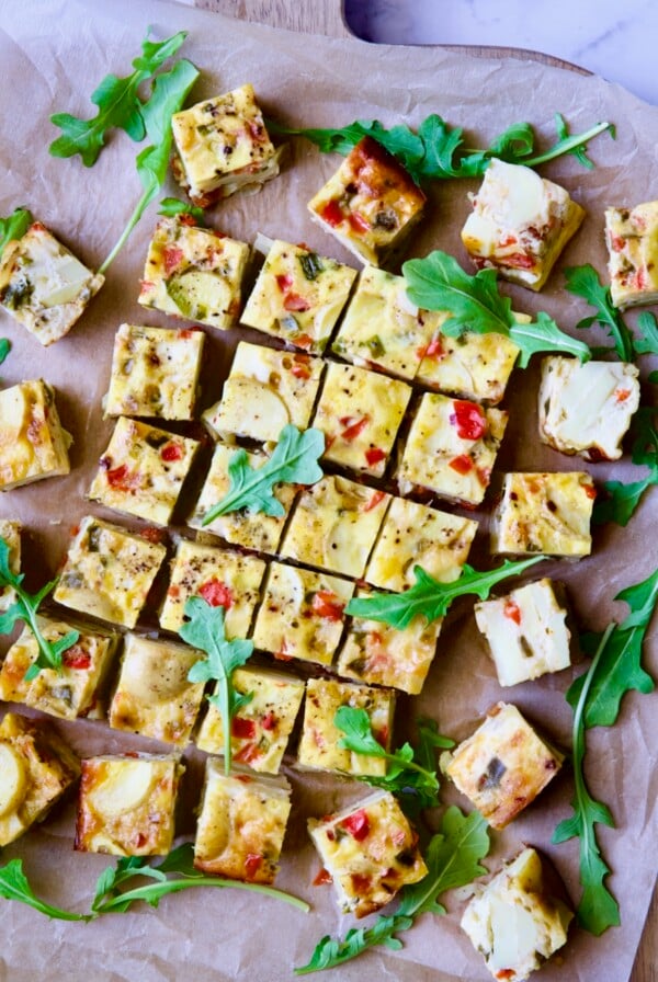 Oven-Baked Spanish Tortilla on cutting board garnished with arugula.