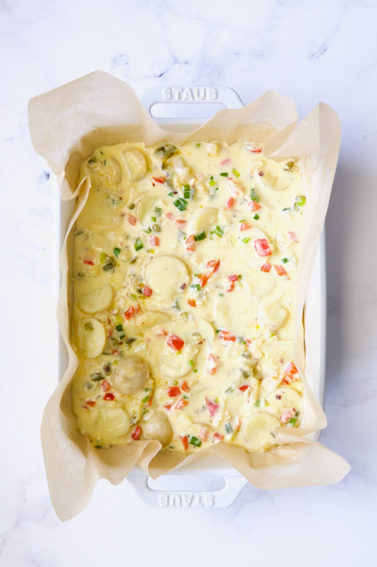 Tortilla in white baking dish before being baked.