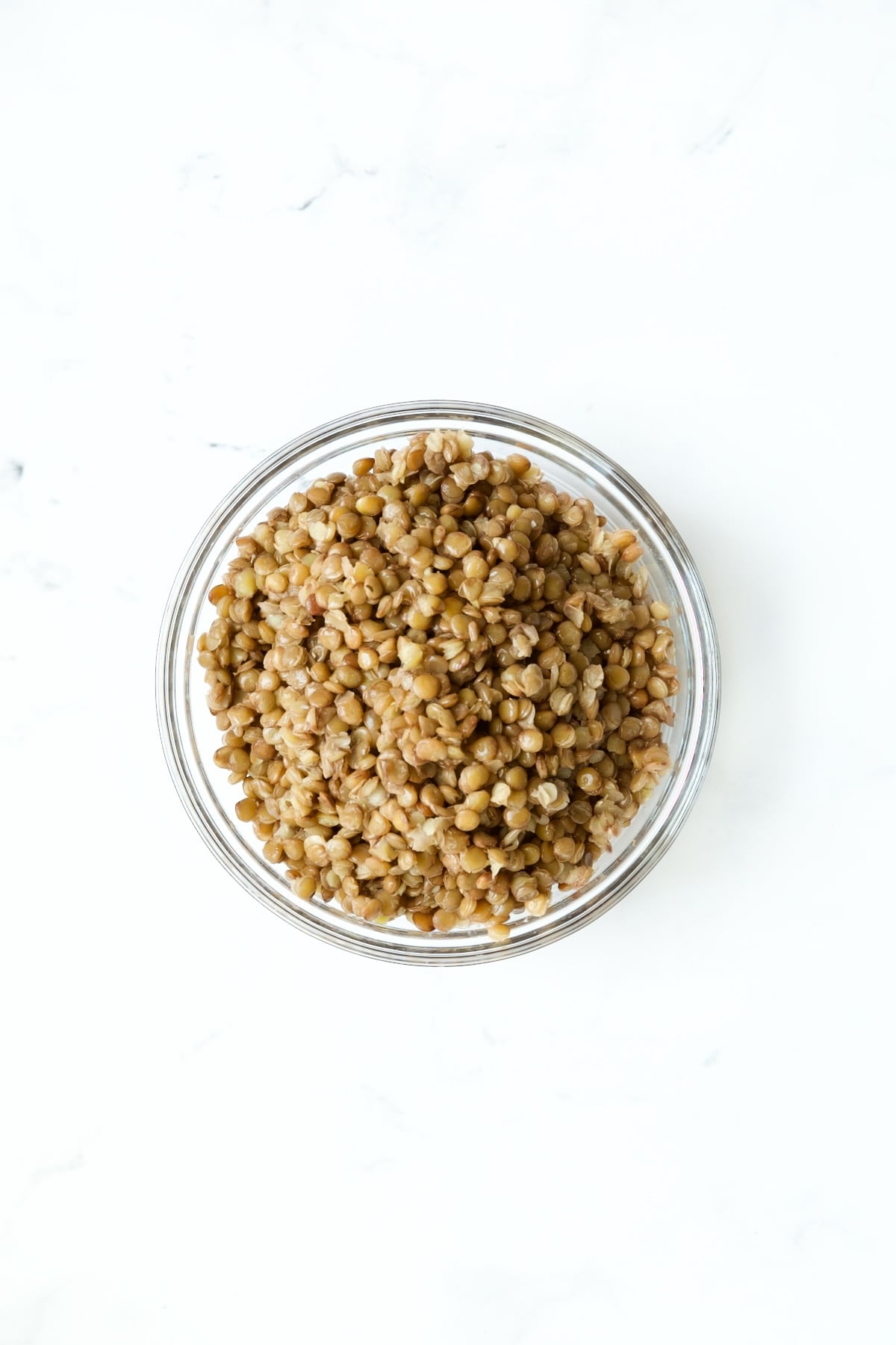 Cooked brown lentils in glass bowls.
