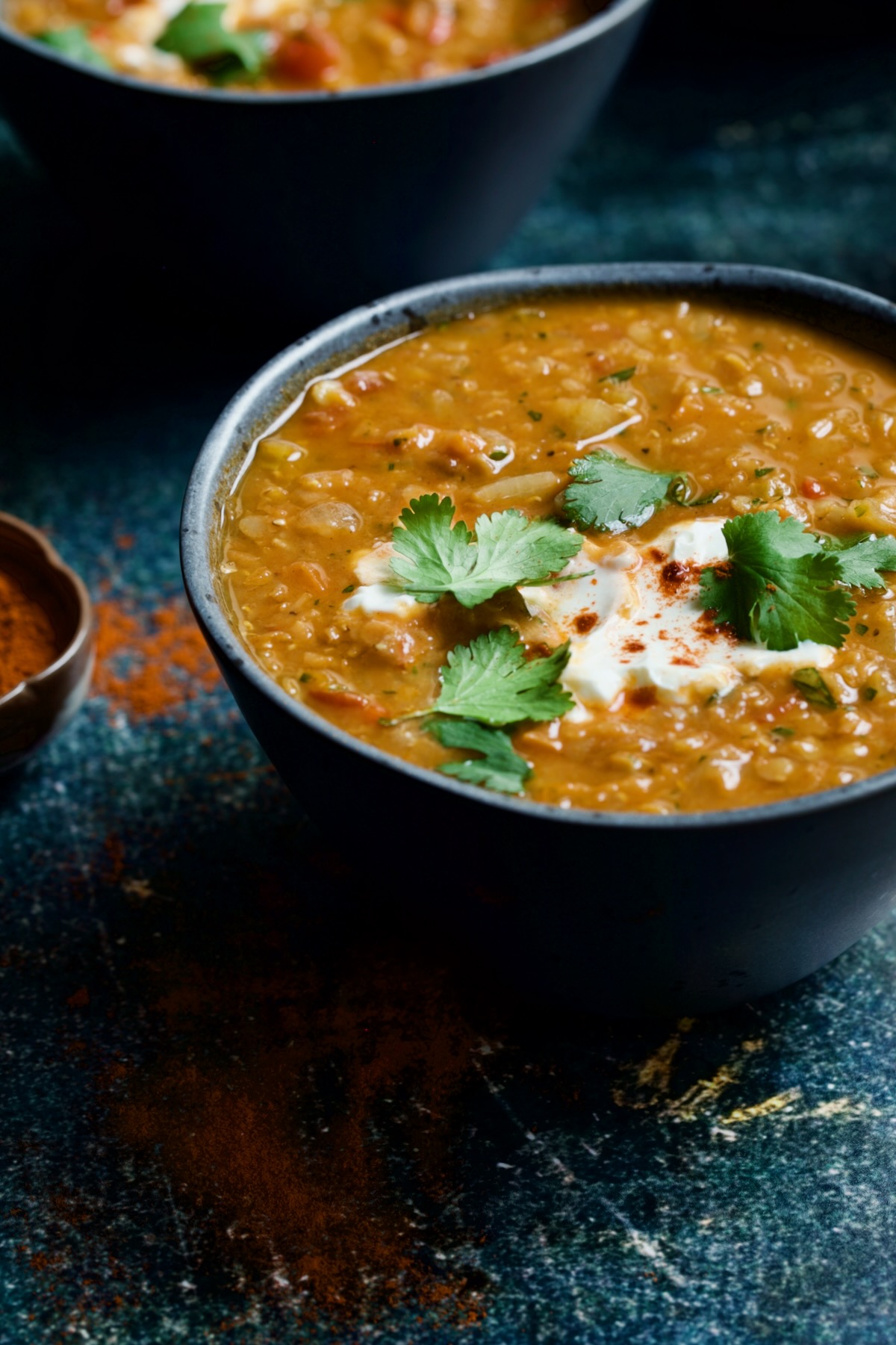 Bowl of Ethiopian Red Lentil Vegetable Soup on blue distressed background.