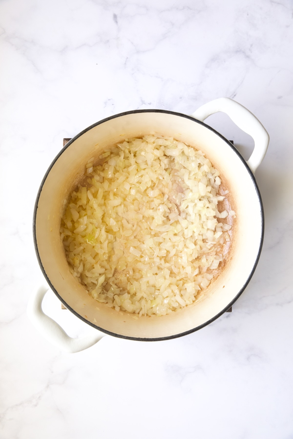 Cooked onions in white Dutch oven.