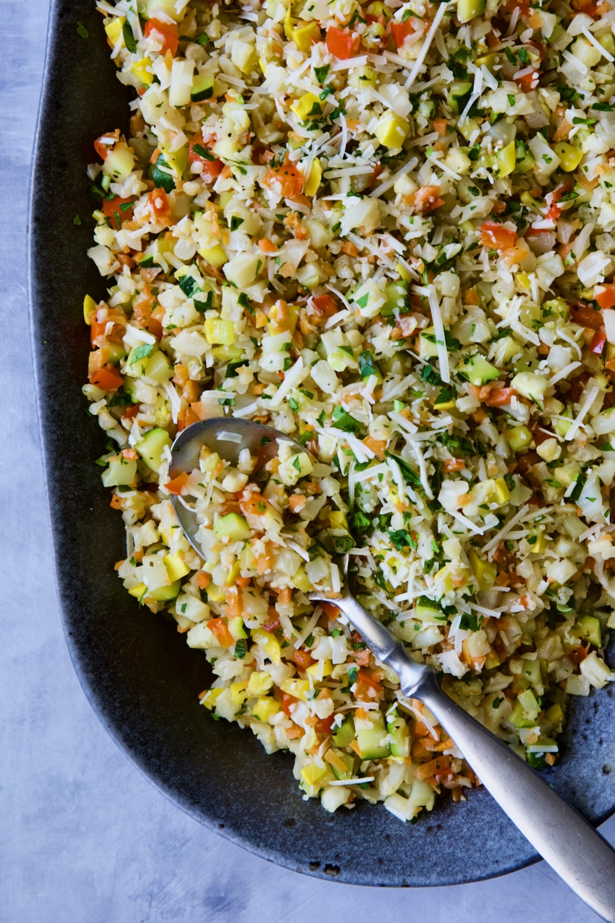 Garlic Parmesan Roasted Vegetable Rice on platter with serving spoon.