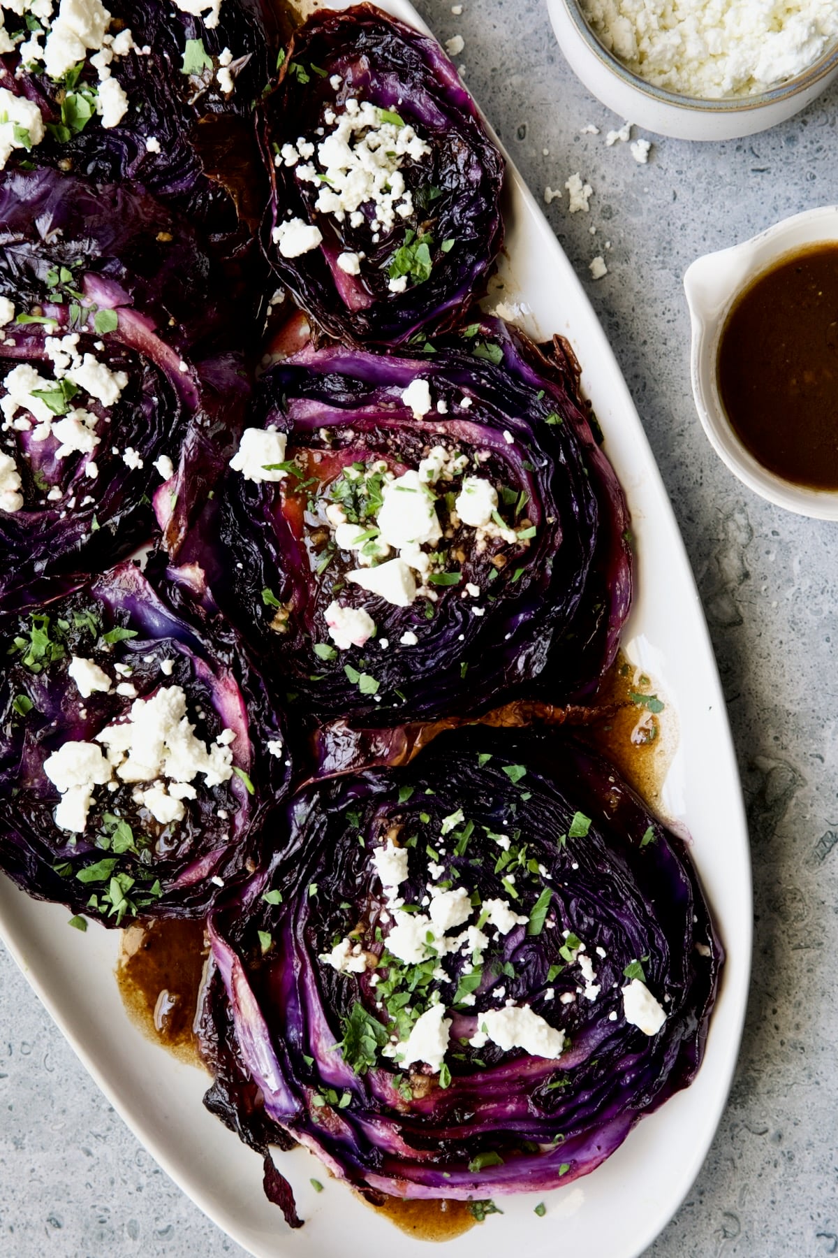 Roasted Red Cabbage Steaks with Balsamic Vinaigrette and Goat Cheese on white platter.