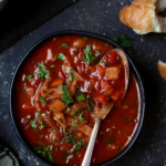 Rustic Cabbage and Root Vegetable Soup in black bowl garnished with parsley.