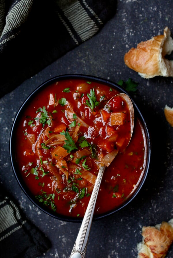 Rustic Cabbage and Root Vegetable Soup in black bowl garnished with parsley.