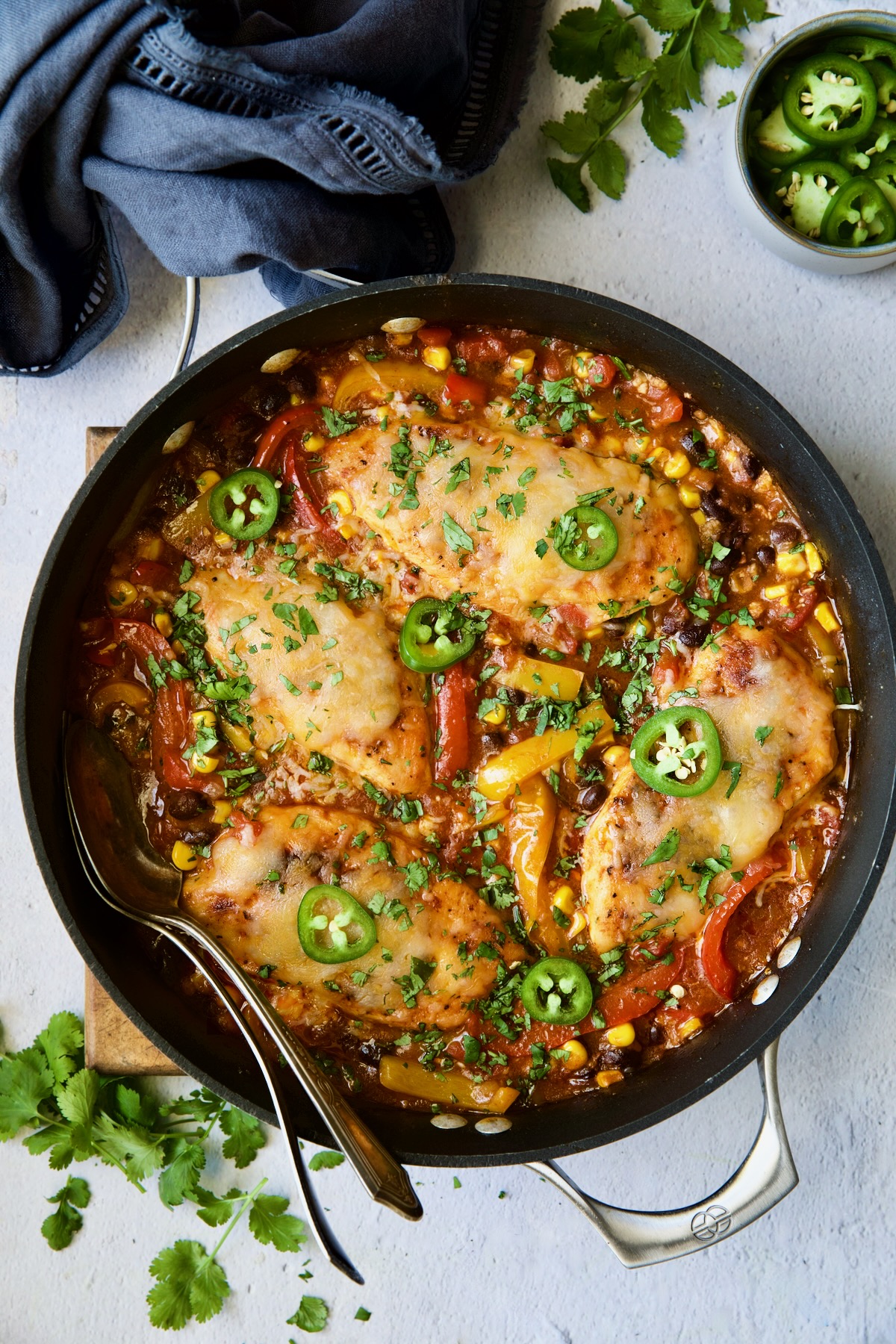 Southwestern Chicken Skillet in the skillet with serving utensils garnished with jalapeno slices and cilantro.