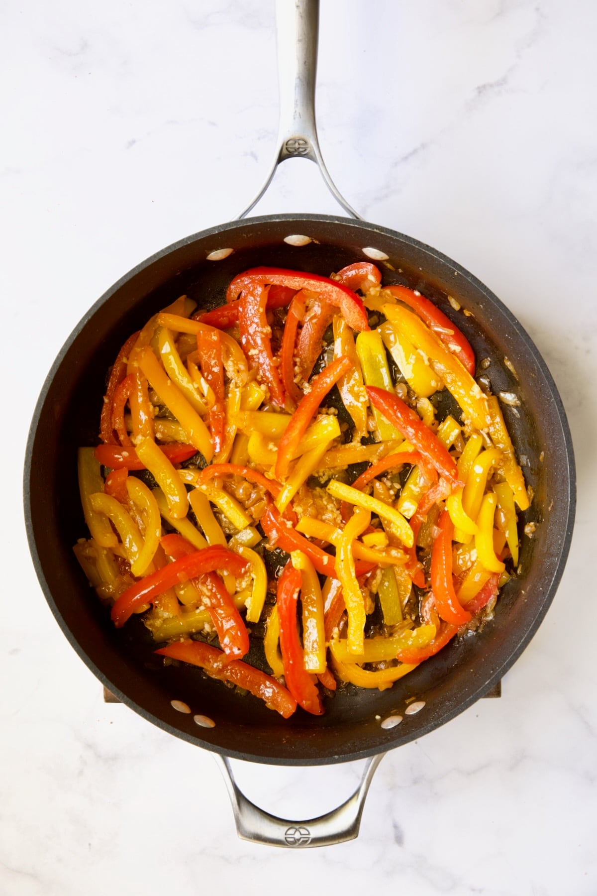 Cooked bell peppers and onions in skillet.