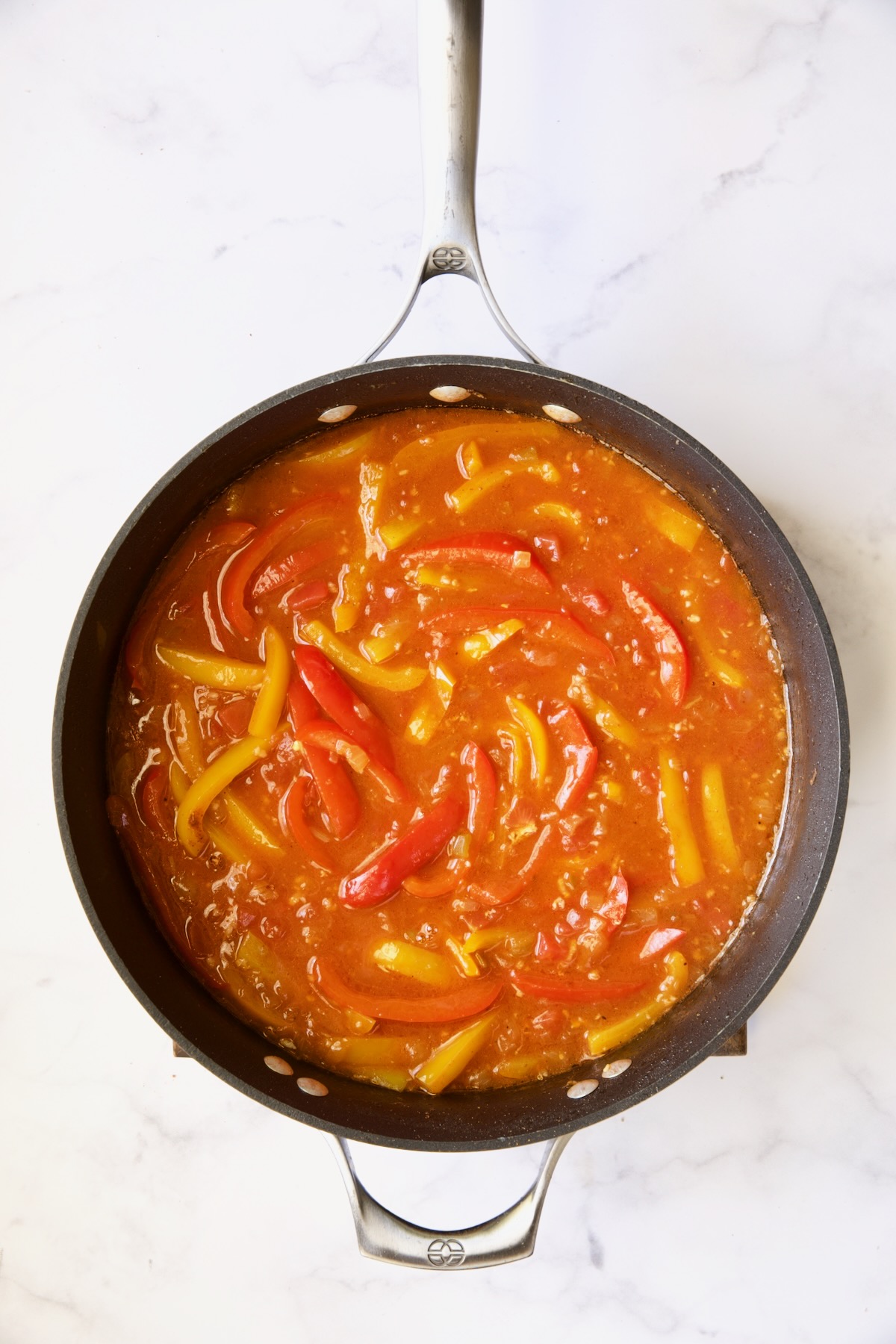 Sauce with bell peppers in skillet.