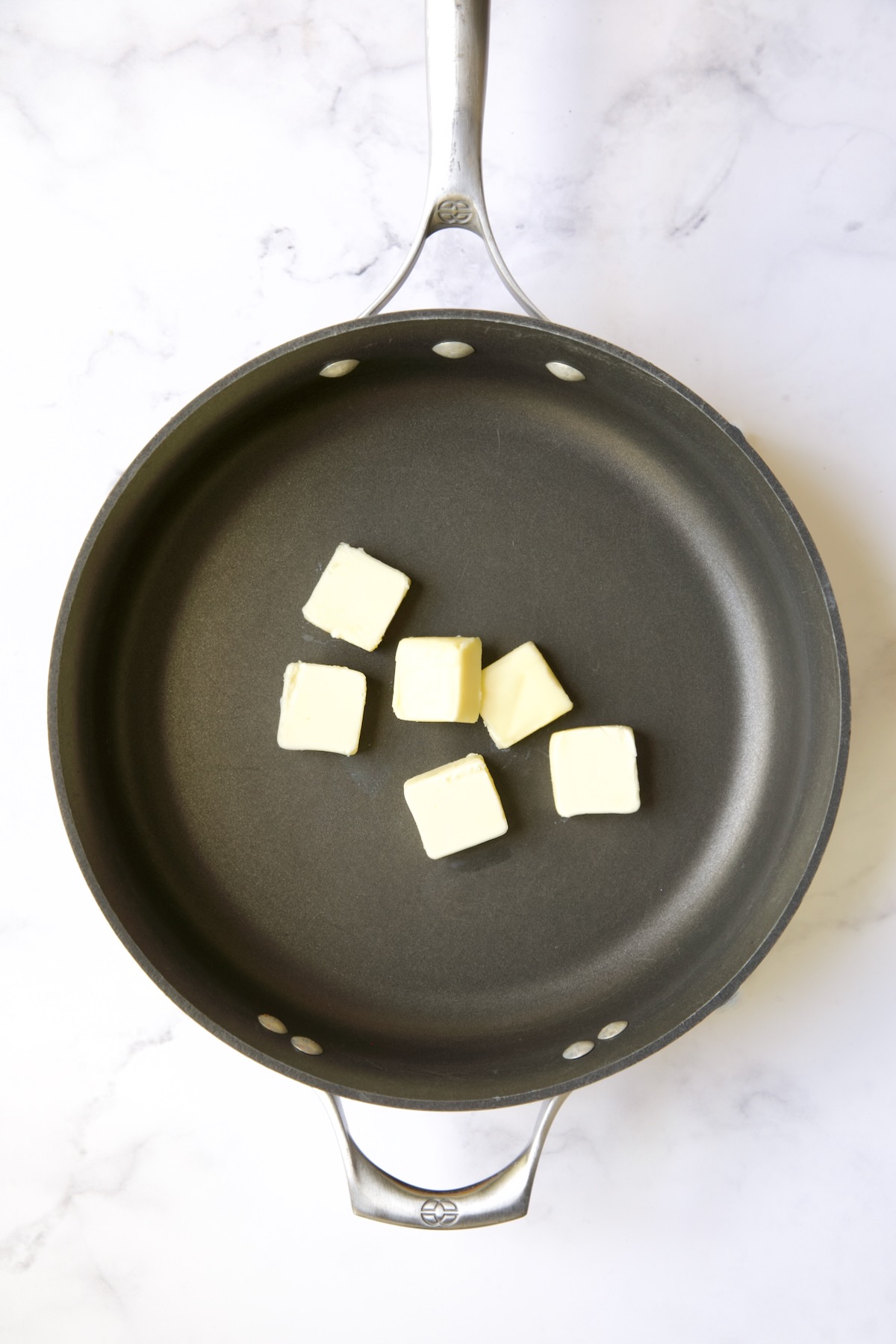 Six pats of butter in nonstick skillet before being melted.