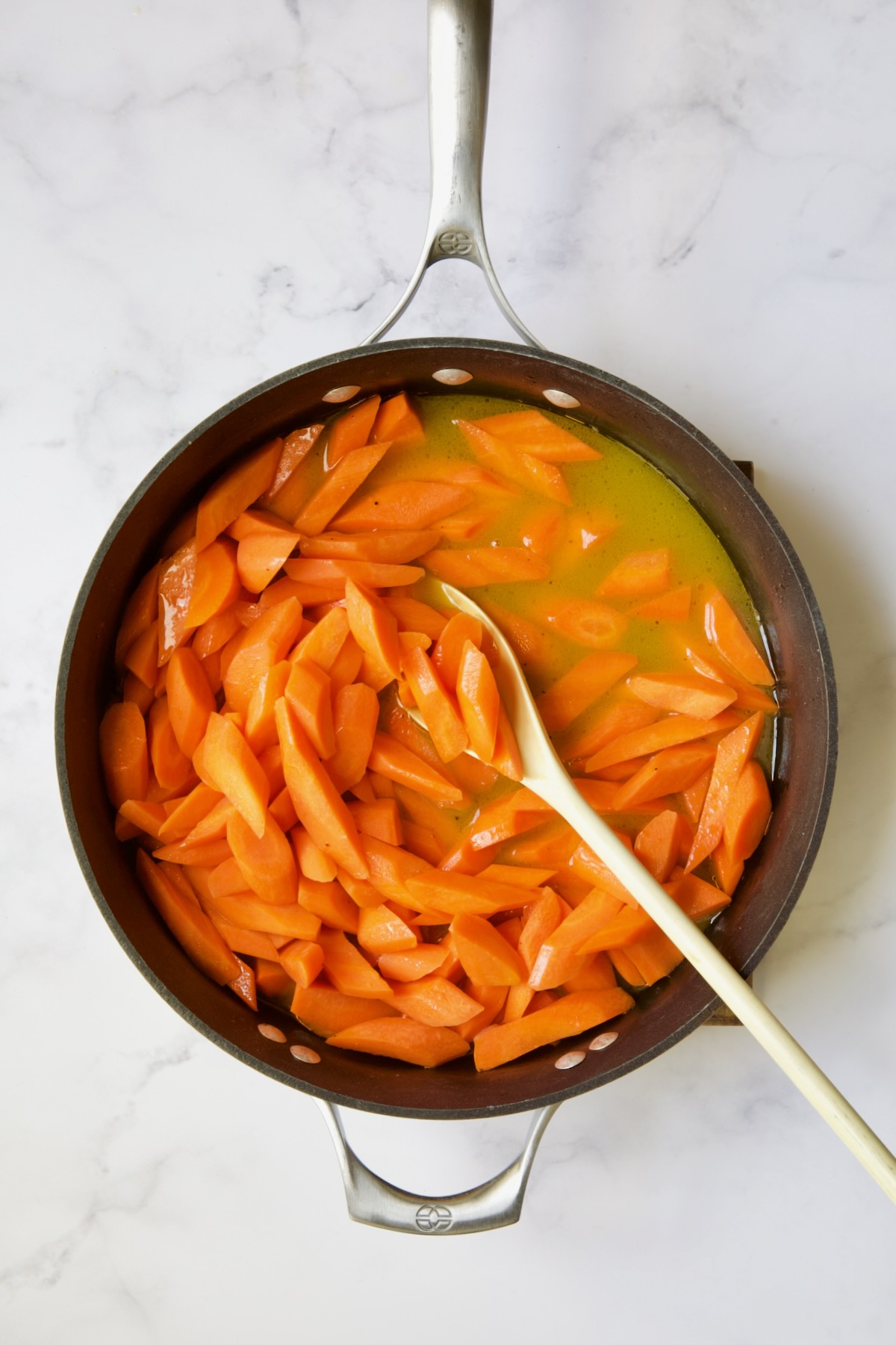 Carrots in glaze ingredients in nonstick skillet.