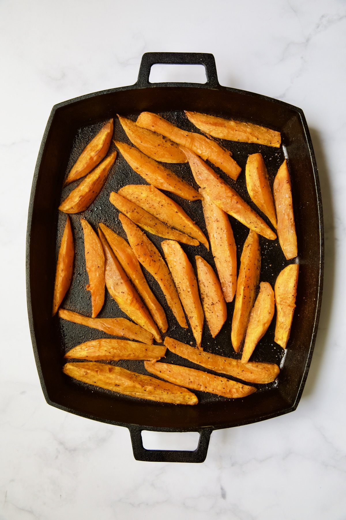 Roasted sweet potatoes on cast iron baking pan.