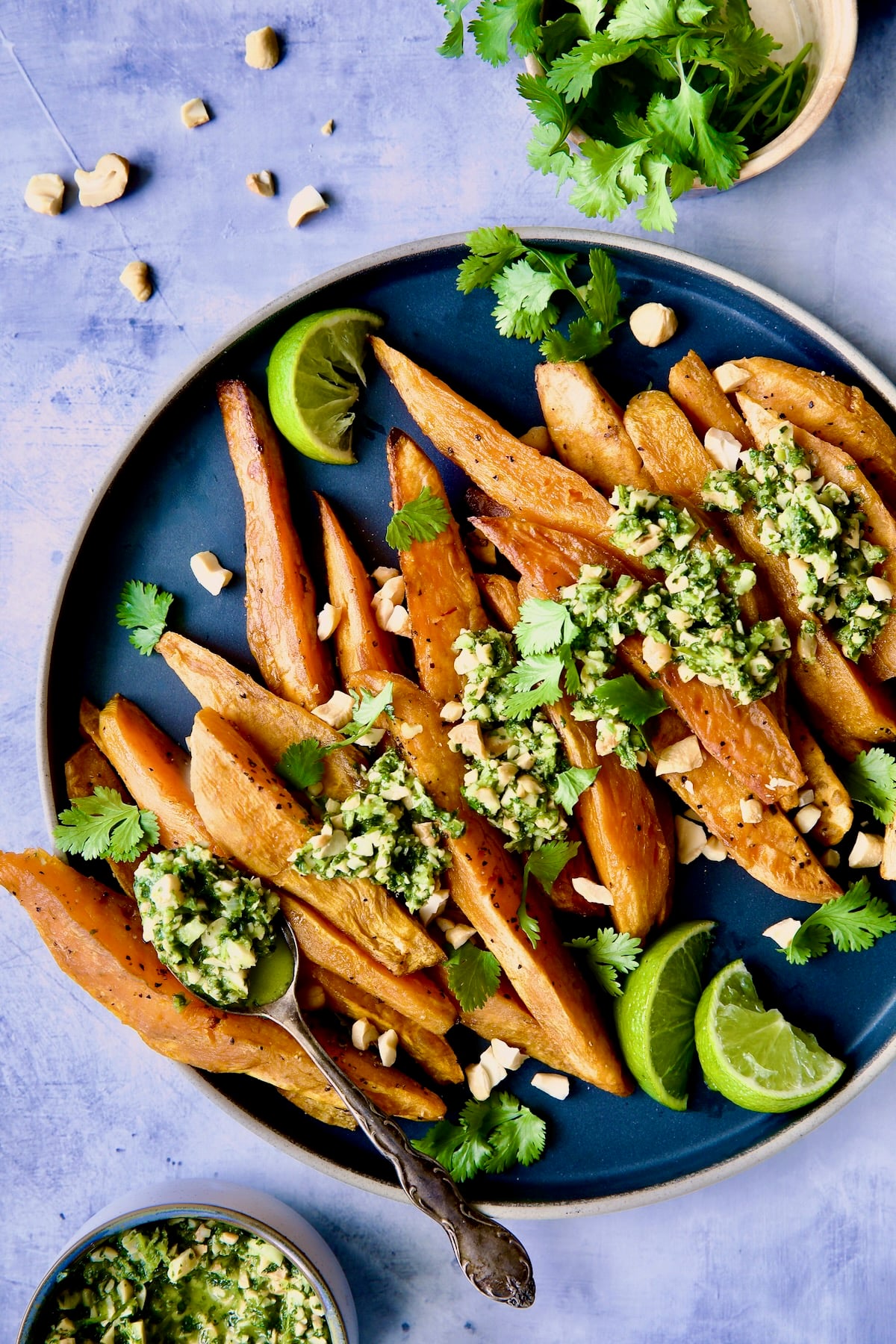 Roasted Sweet Potato Wedges with Cilantro - Cashew Sauce on round plate with cilantro and lime wedges.