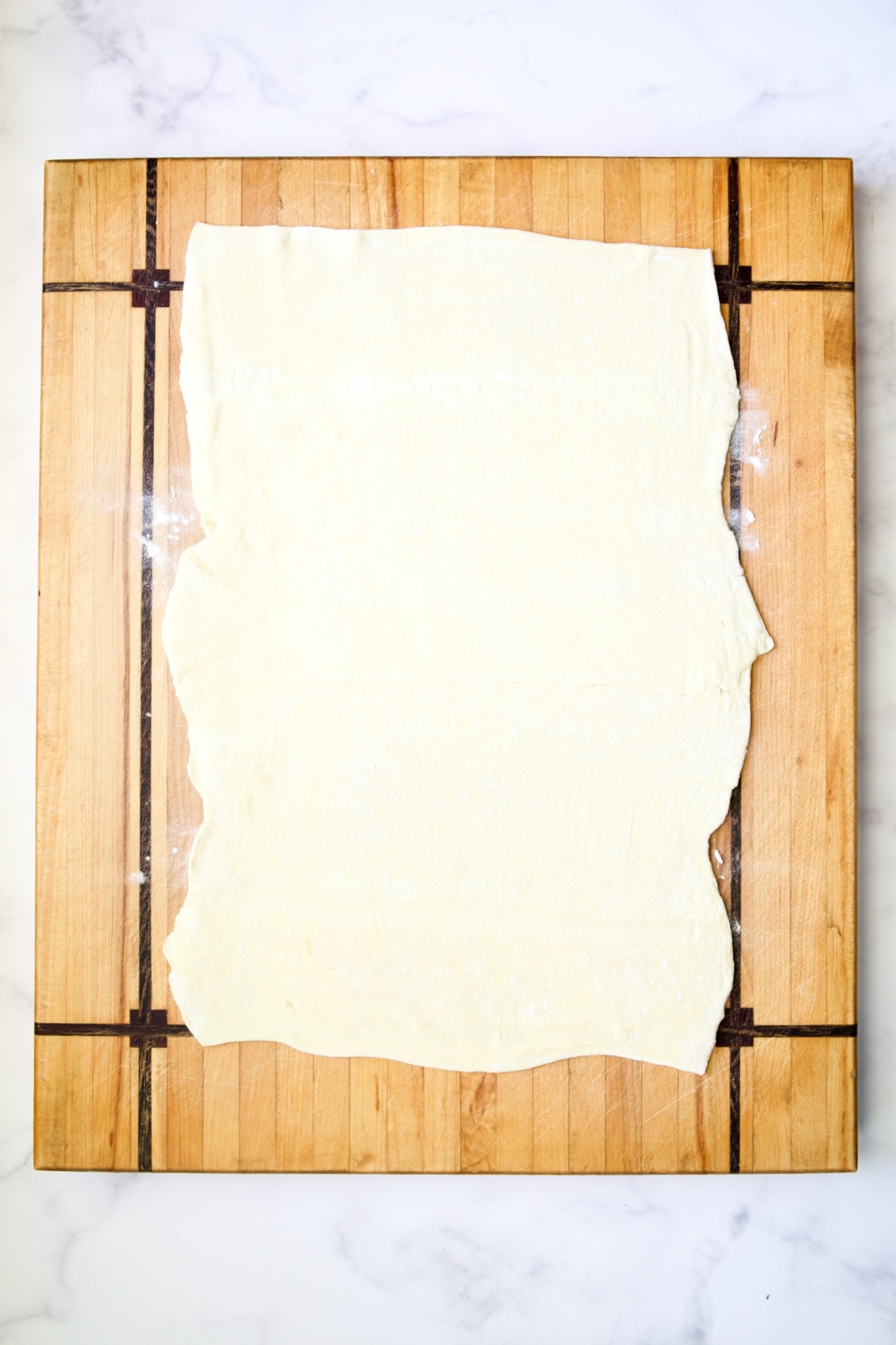 Puff pastry on wood cutting board.