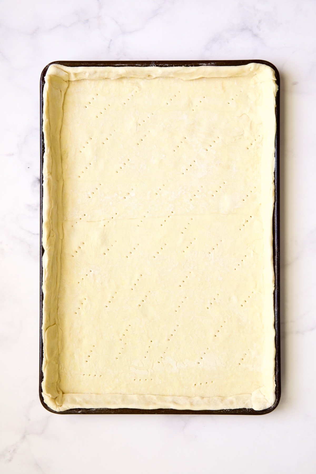 Puff pastry crust docked with fork holes.