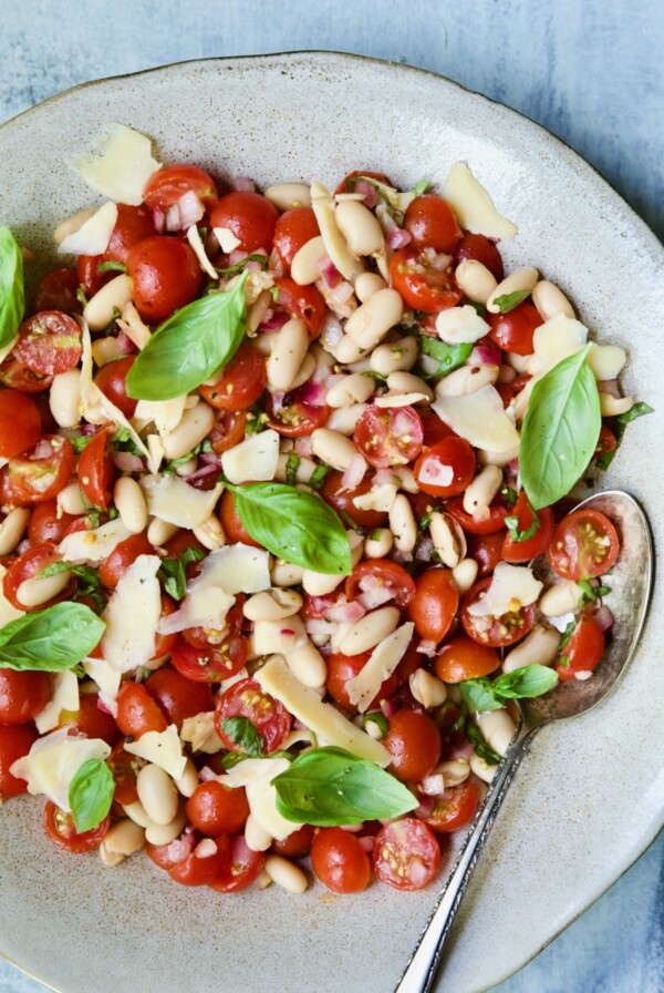 Tuscan Cherry Tomato and White Bean Salad in serving bowl with serving spoon.