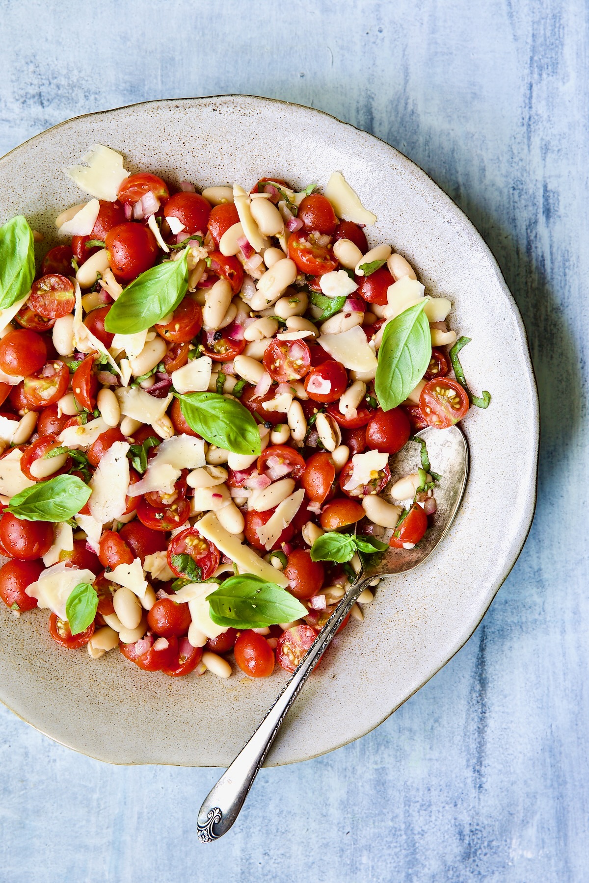 Tuscan Cherry Tomato and White Bean Salad in serving bowl with serving spoon.
