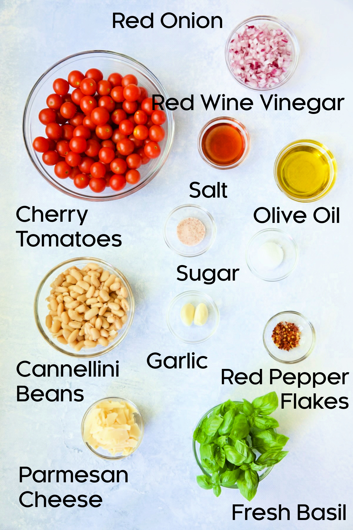 Ingredients for Tuscan Cherry Tomato and White Bean Salad in glass bowls.