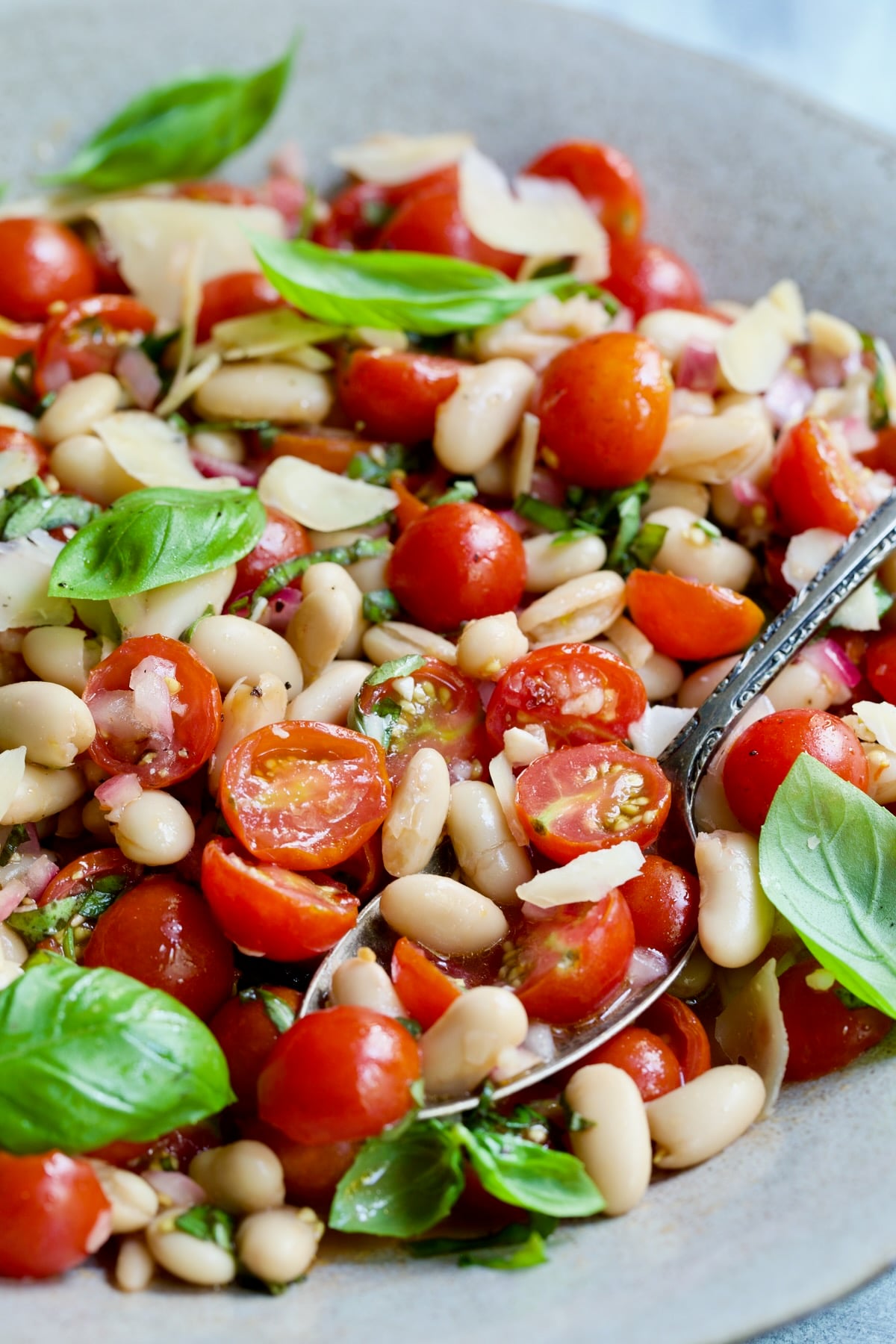 Serving spoon scooping up Tuscan Cherry Tomato and White Bean Salad.