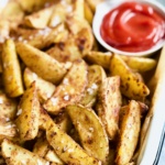 Perfect Roasted Potato Wedges with ketchup in white enamel tray.
